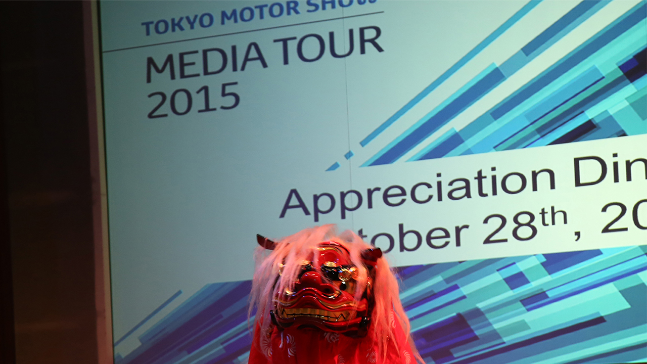 東京モーターショー海外メディア向けイベントで獅子舞演舞。背景にモーターショーの文字。